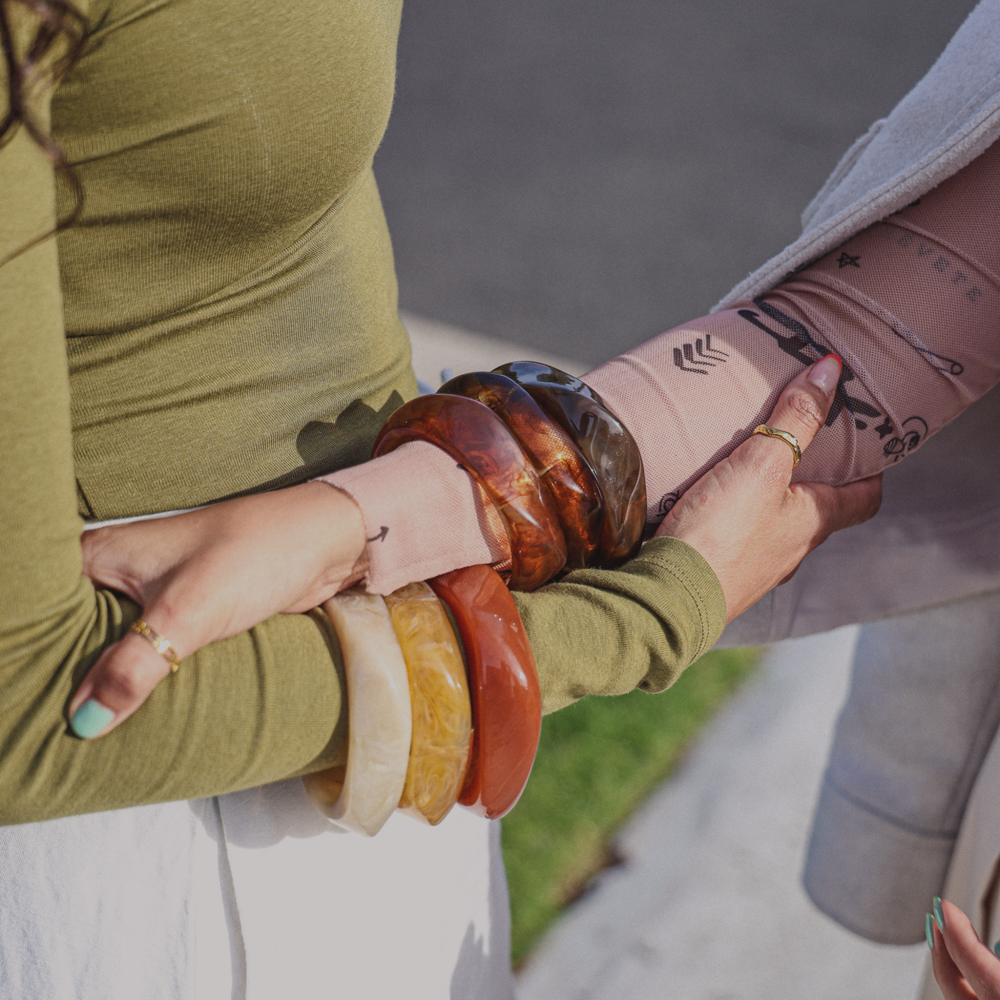 Model wearing chunky resin bangles stack with neutral outfit