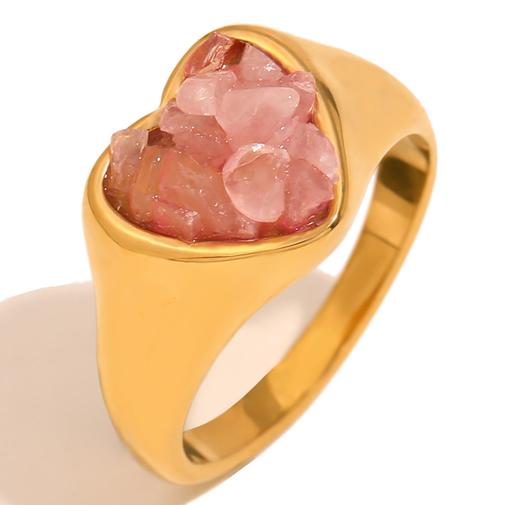 Close up of Mila Online Shop Gemstone Heart Ring in gold with pink heart cut gemstone, elegant chunky statement ring styled with gold stackable rings