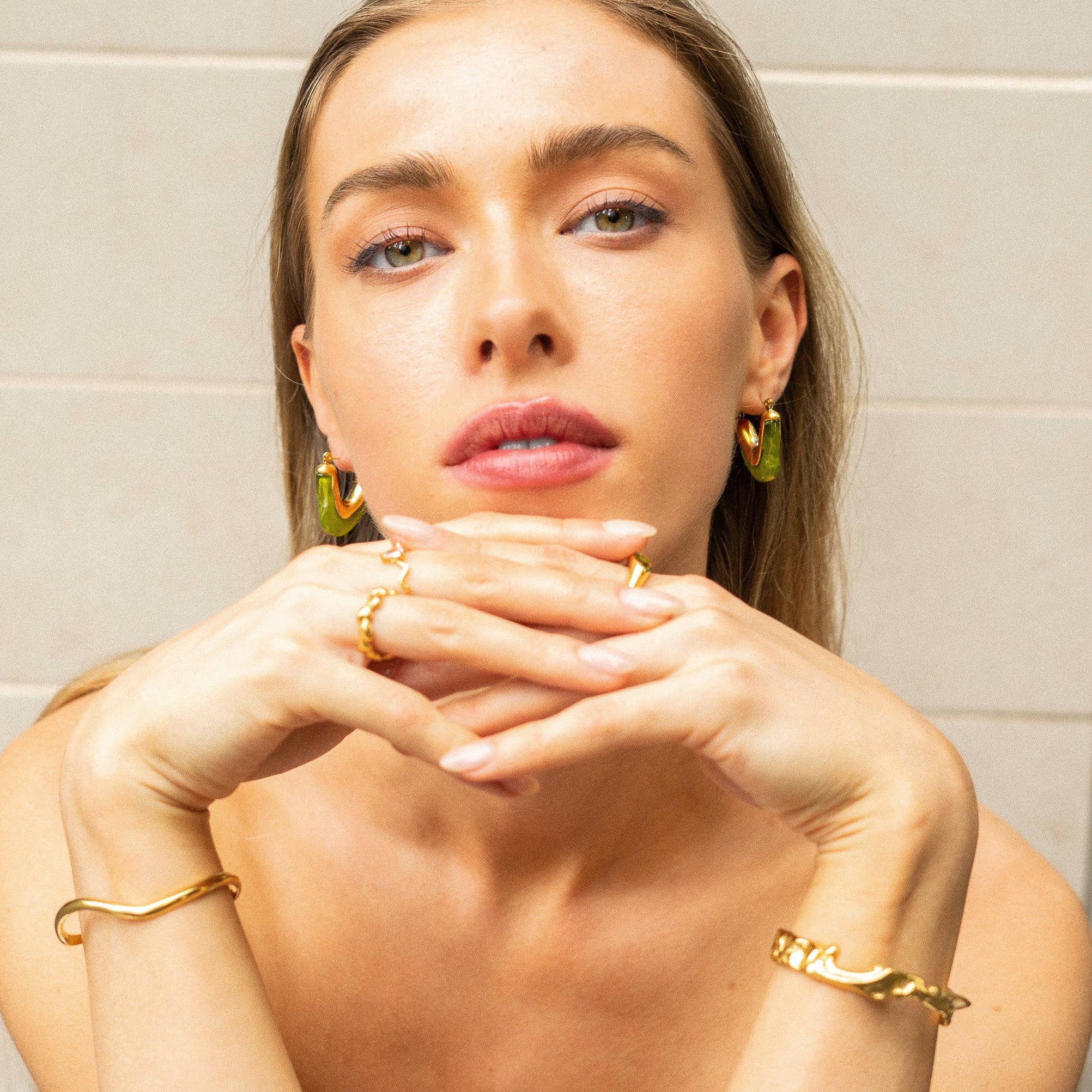 Model wearing vivid green Mia Resin Hoops by Mila Online Shop, styling bangles and rings for a cohesive, fashion-forward jewellery look.