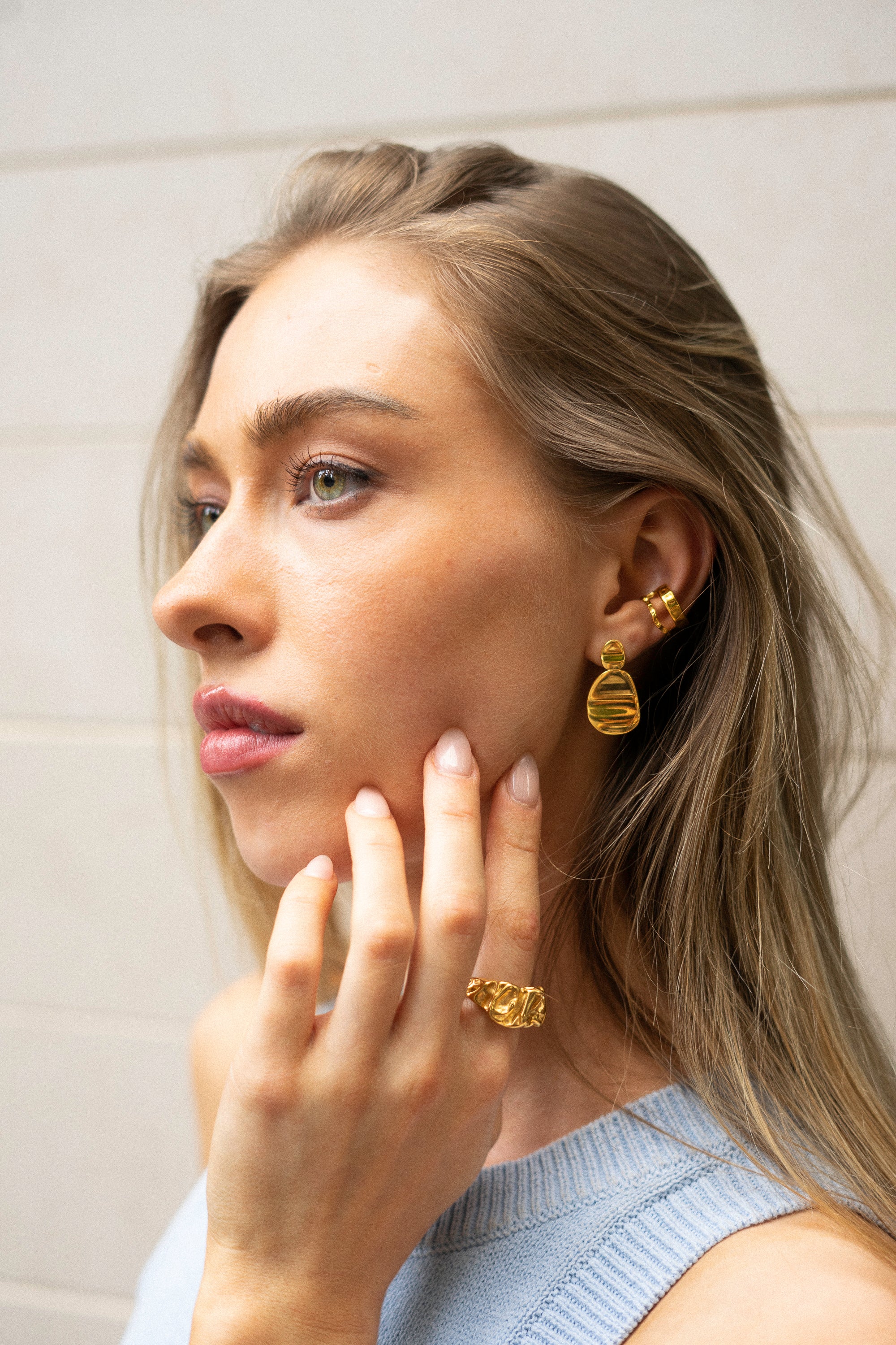 Model wearing gold Click Stud Earrings styled with a matching ear cuff – bold and elegant statement studs for a refined everyday look.