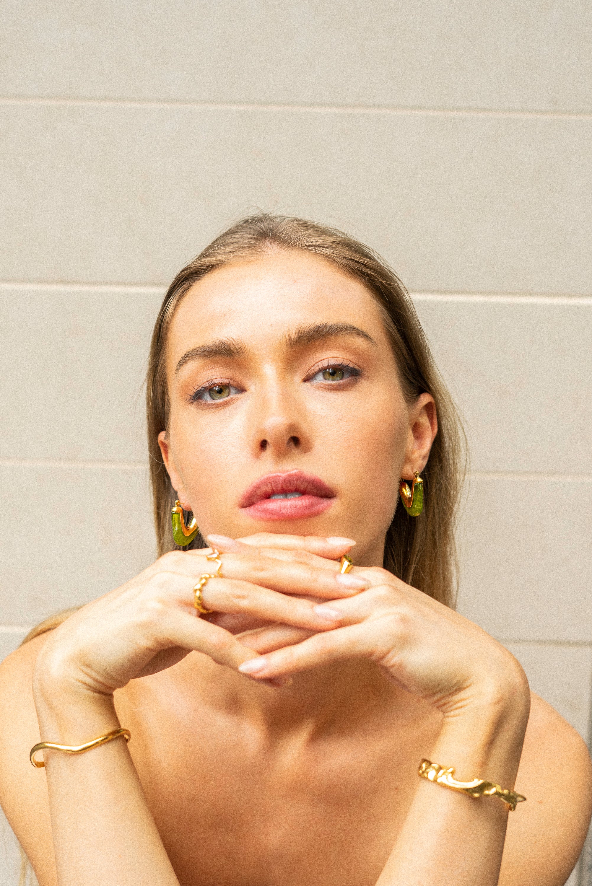 Model wearing vivid green Mia Resin Hoops by Mila Online Shop, styling bangles and rings for a cohesive, fashion-forward jewellery look.